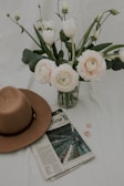 A close-up of a soft, pastel pink beret resting on a vintage wooden table with delicate flowers nearby.