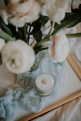 A morning coffee setup by a window with a small vase of fresh flowers.