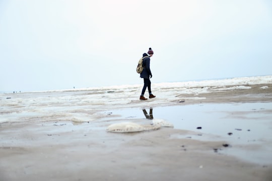 person in black jacket walking on beach during daytime in Jūrmala Latvia