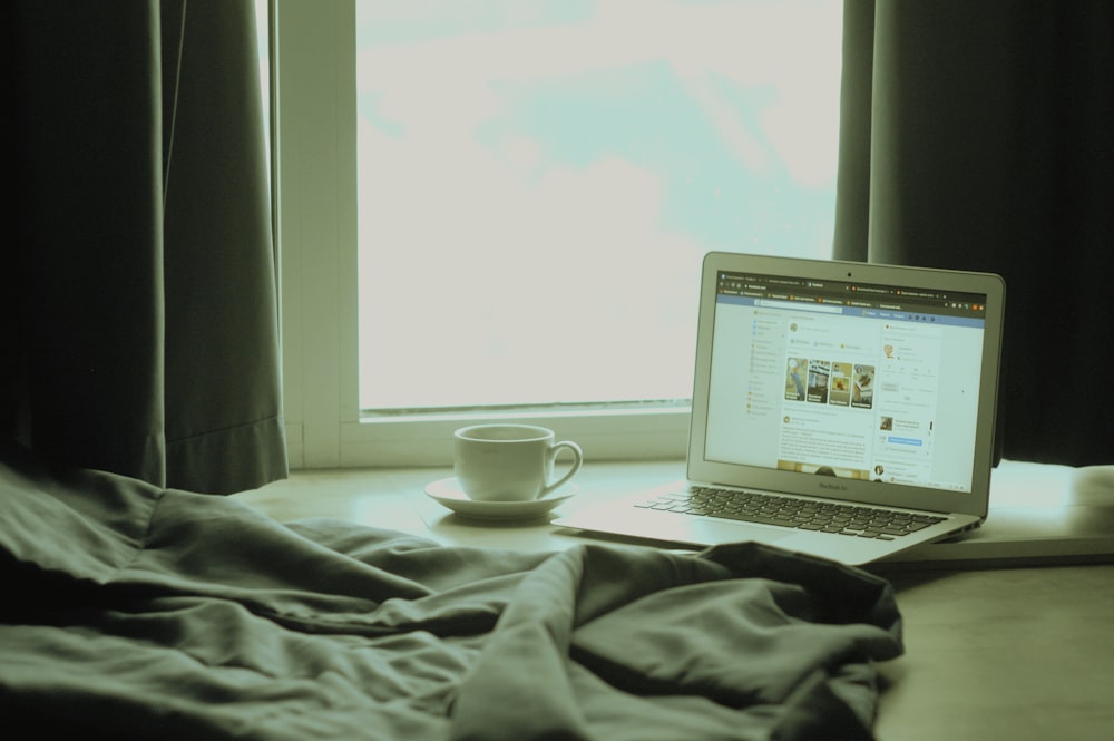 white laptop computer on bed