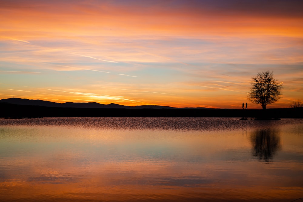 silhouette of mountain near body of water during sunset