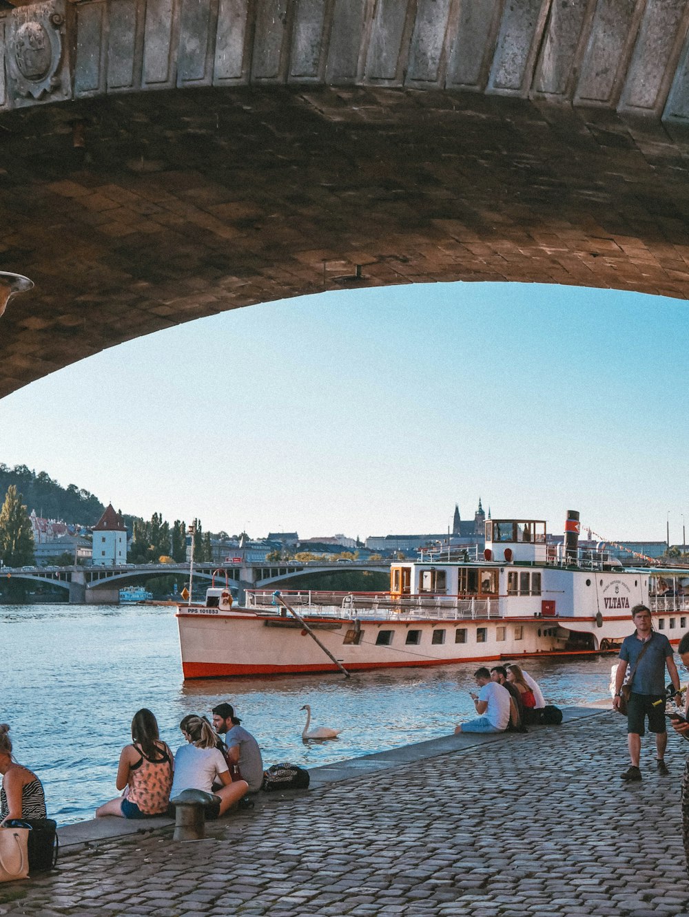 people on boat under arch bridge during daytime