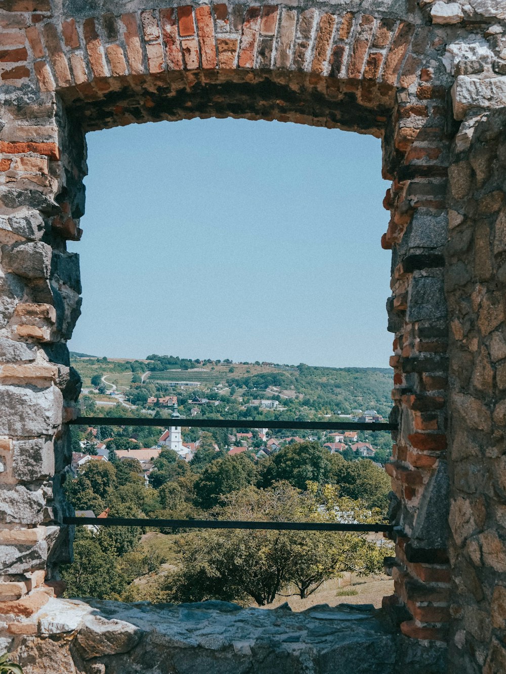 brown brick arch with green trees in the distance