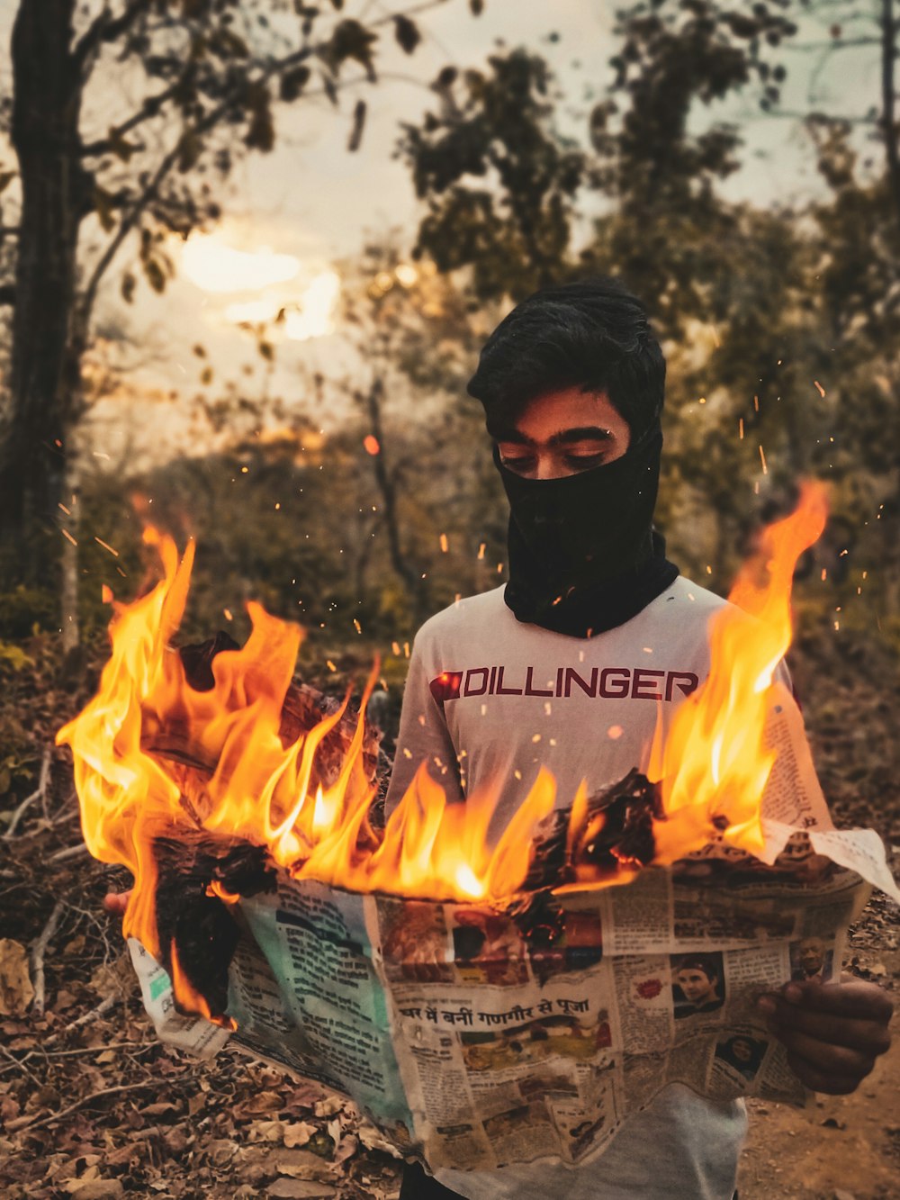 Un uomo con una maschera nera che tiene un giornale con il fuoco che esce da esso