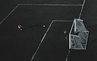 A cinematic wide shot of a footballer practicing free kicks under stadium lights at dusk.