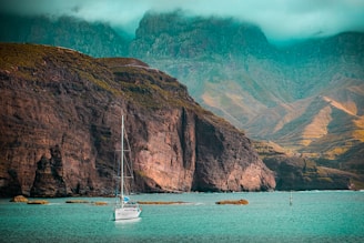 white boat on sea near brown mountain during daytime