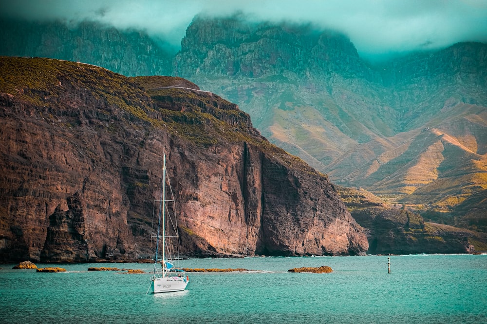 white boat on sea near brown mountain during daytime