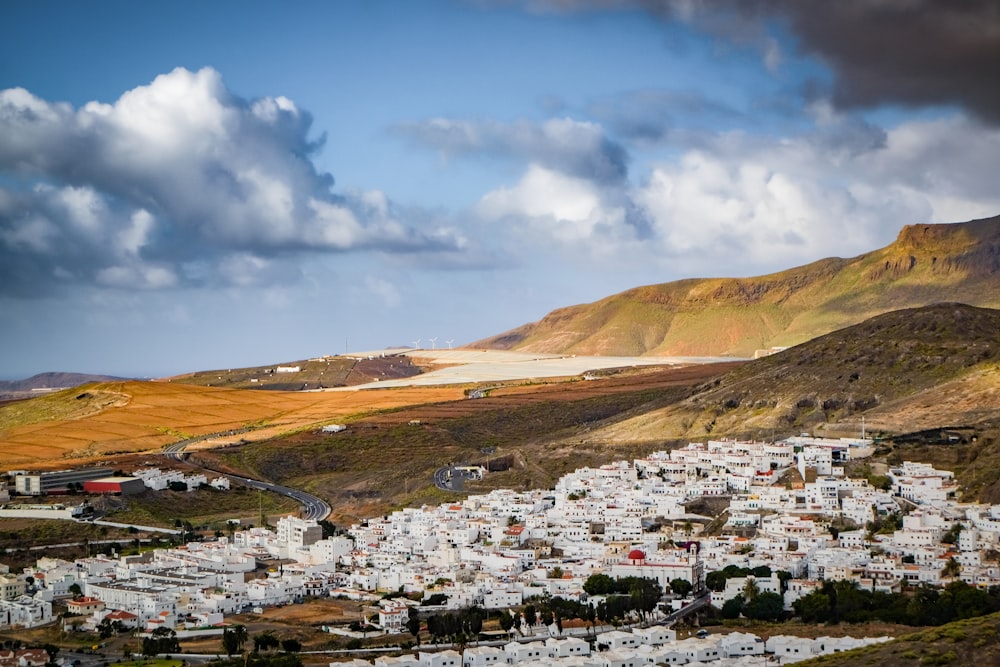 white and brown houses near brown mountain under blue sky during daytime