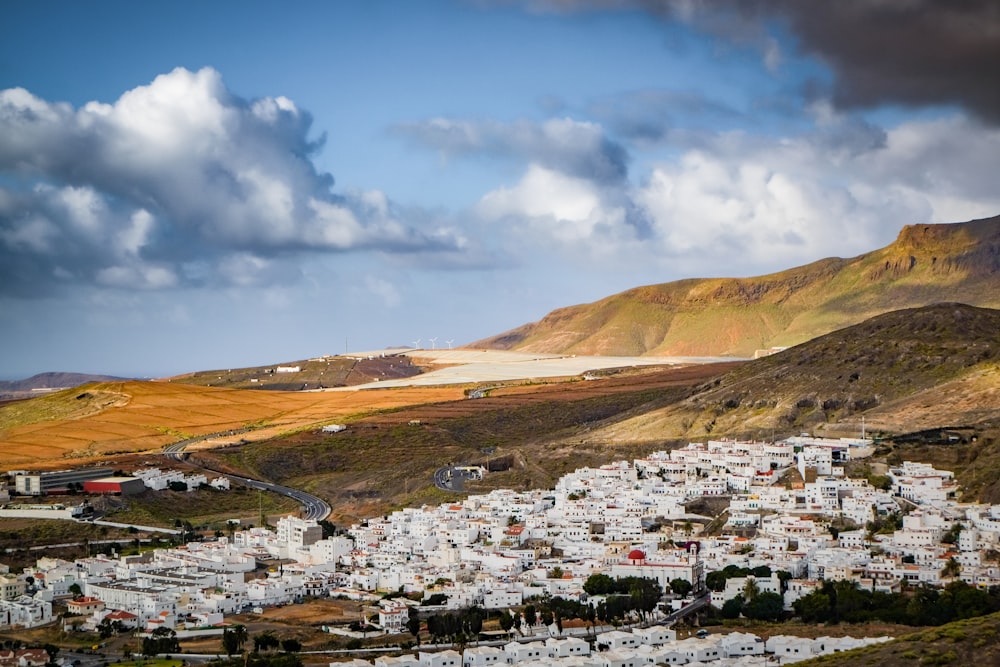 casas brancas e marrons perto da montanha marrom sob o céu azul durante o dia