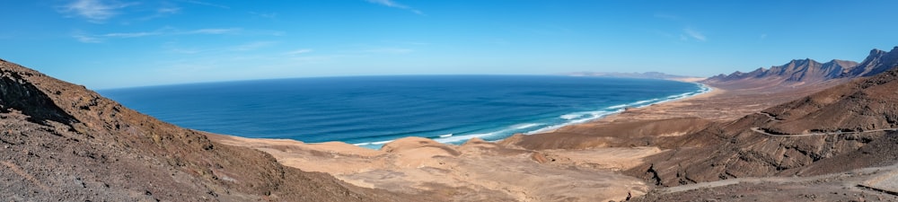 sabbia marrone vicino al mare blu sotto il cielo blu durante il giorno