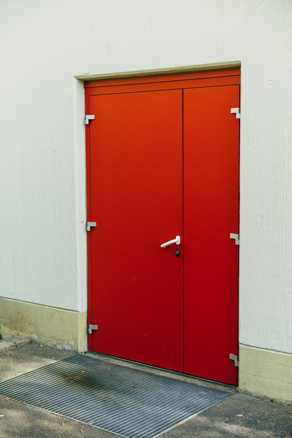una porta rossa sul lato di un edificio bianco