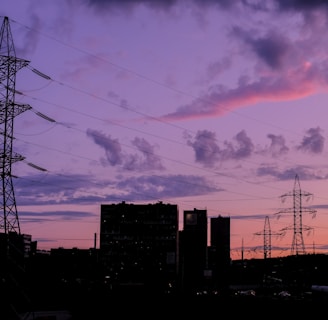 silhouette of buildings under cloudy sky during sunset powered by solar