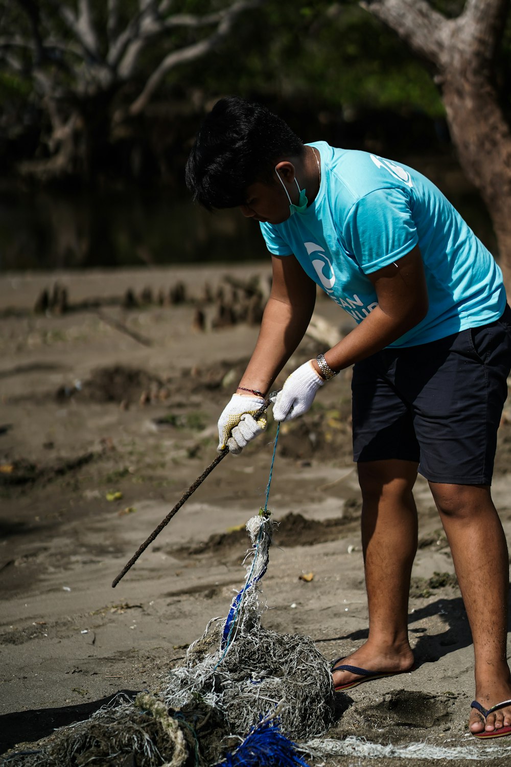 man in blue t-shirt and black shorts holding a white rope