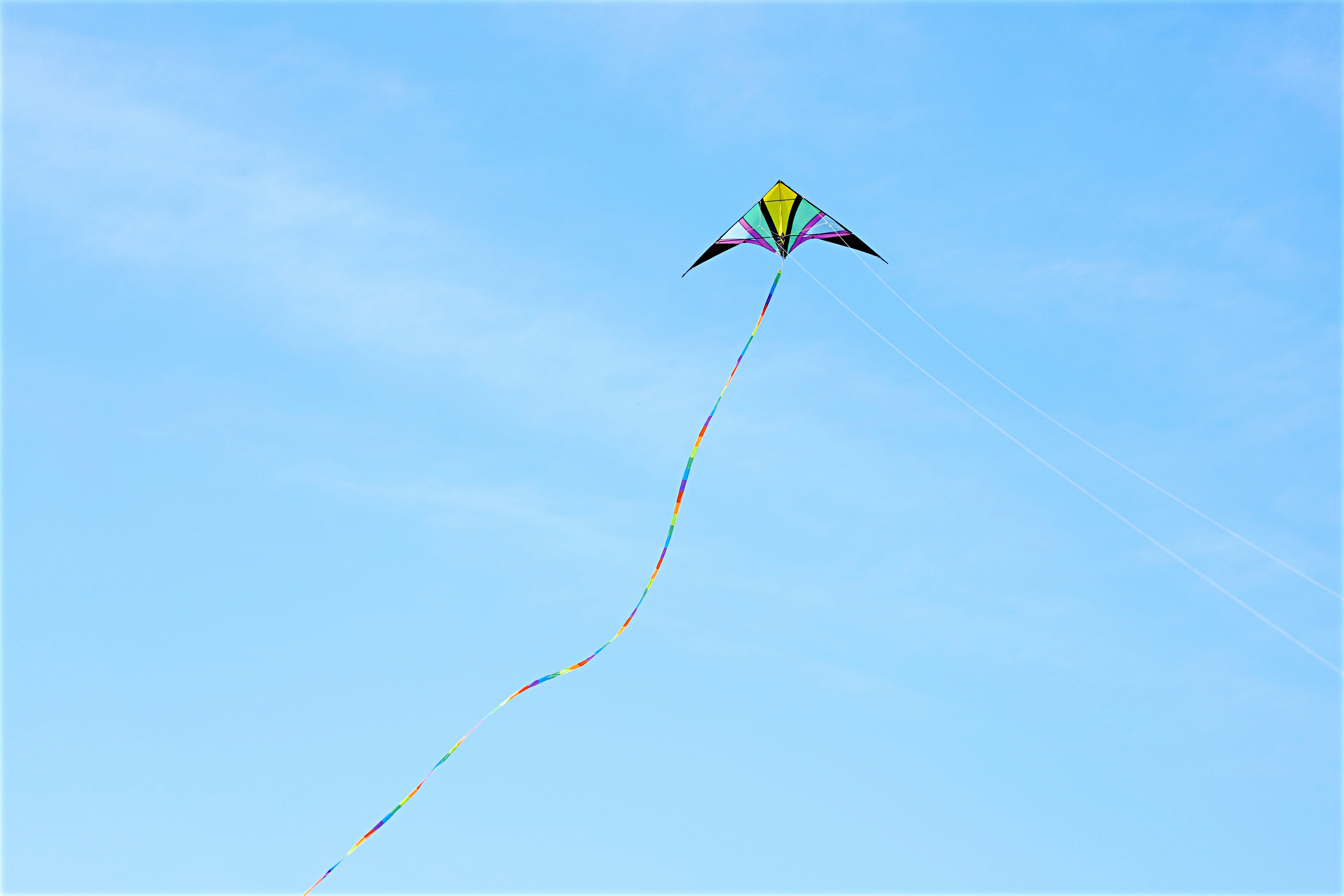 yellow green and blue kite flying under blue sky during daytime