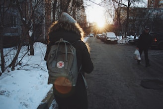 woman in black jacket and brown backpack standing on road during daytime
