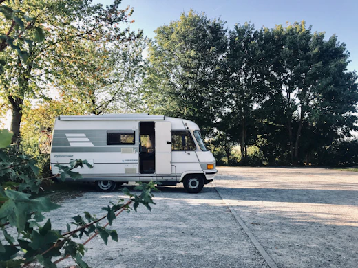 Class C motorhome parked under trees
