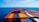 A vast array of colorful shipping containers stacked on the deck of a cargo ship, set against the expansive blue ocean and sky.