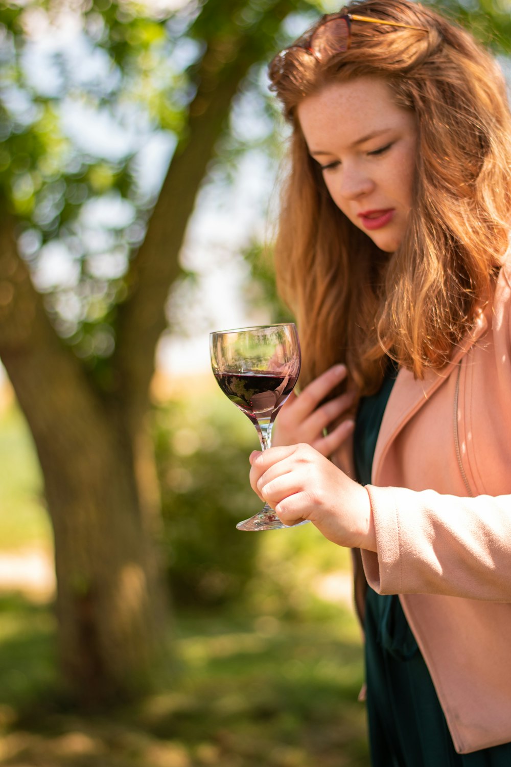 donna in camicia bianca a maniche lunghe che tiene il bicchiere di vino