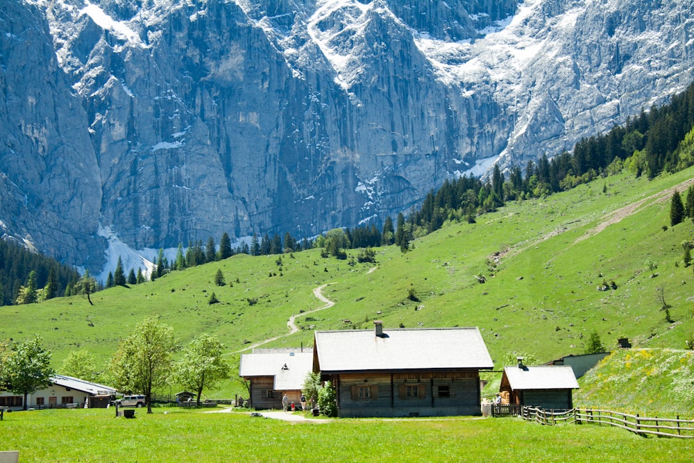 山の近くの緑の芝生のフィールドに白と茶色の家