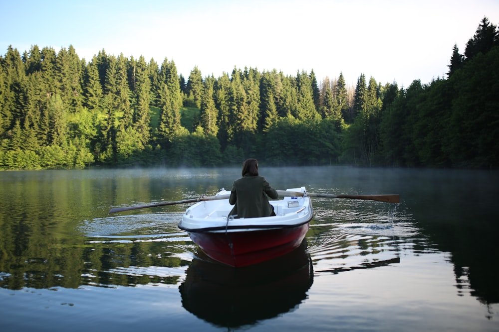 man in red and white boat on lake during daytime