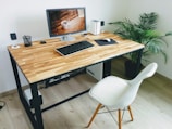 A modern workspace with a compact desk, ergonomic chair, and a potted plant adding a touch of green.