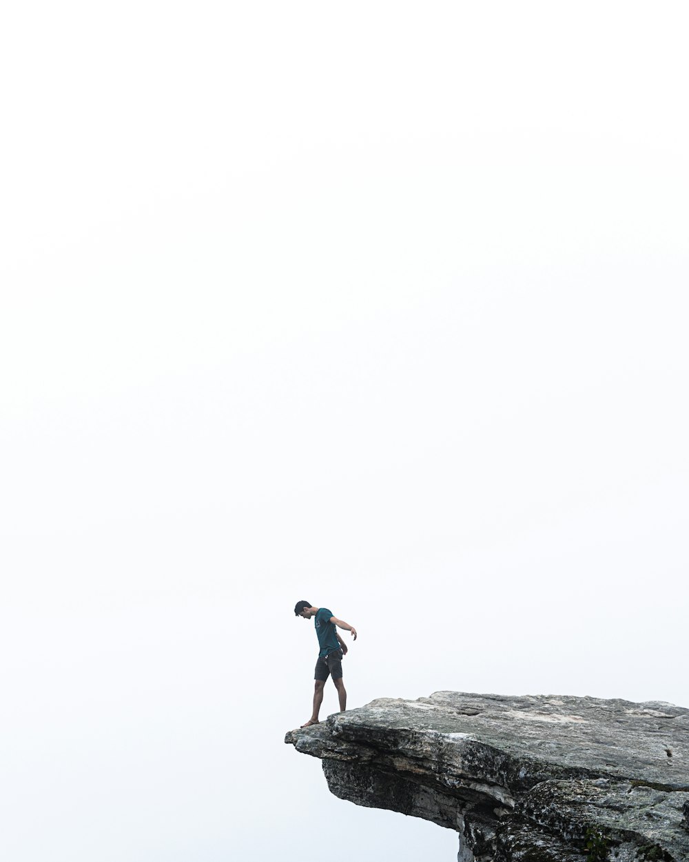 man in black shirt standing on rock