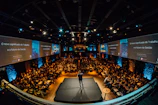 Wide shot of a corporate seminar with attentive participants and a speaker.