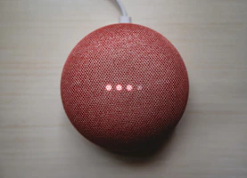 A compact TV box device with glowing LED lights on a wooden table
