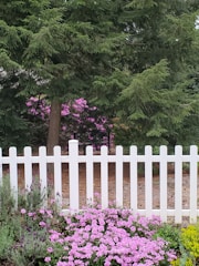 White PVC fence surrounding a garden with flowers.