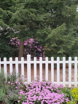 White PVC fence surrounding a garden with flowers.
