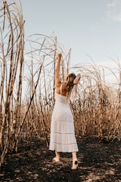 woman in white dress standing on brown grass field during daytime
