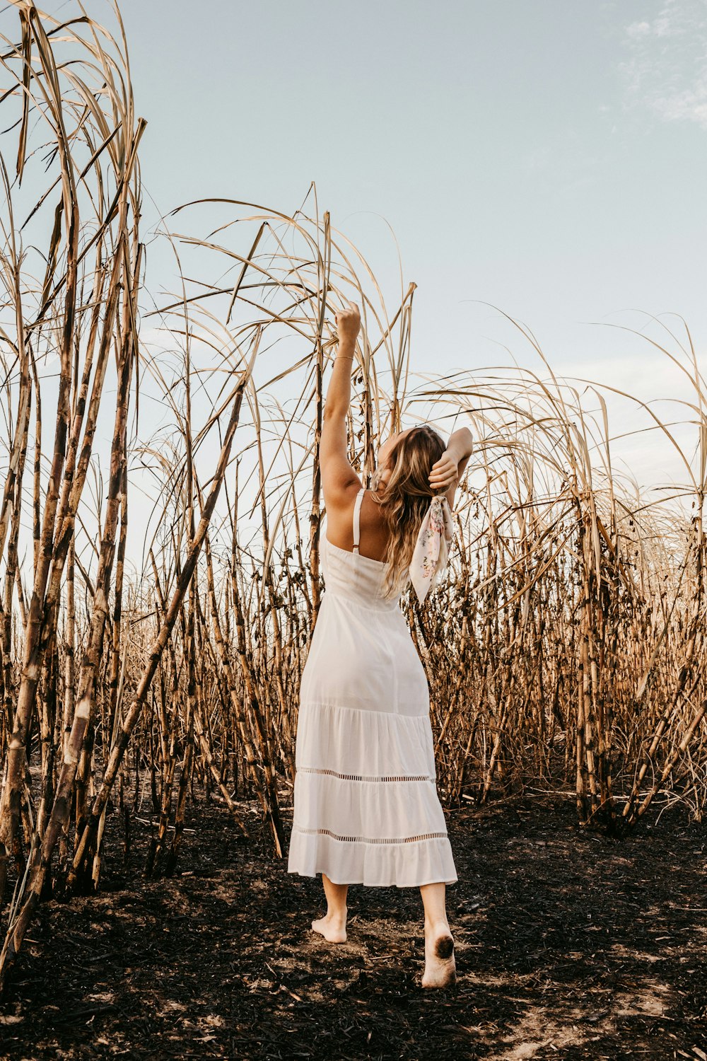 Mujer en vestido blanco de pie en el campo de hierba marrón durante el día