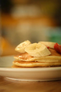 A warm stack of pancakes drizzled with tropical fruit syrup and sprinkled with coconut flakes.