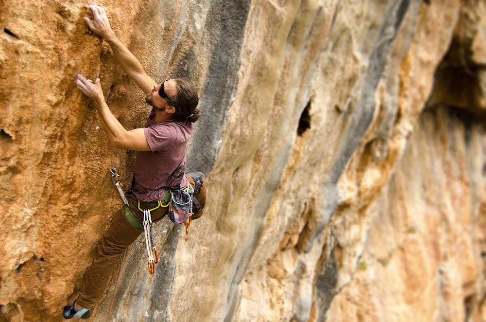 woman climbing on brown rock formation during daytime