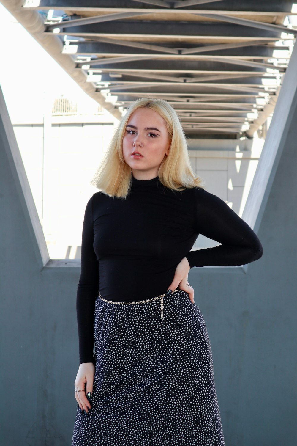 woman in black long sleeve shirt standing near gray wall