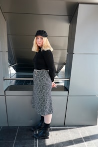woman in black and white dress standing near gray wall