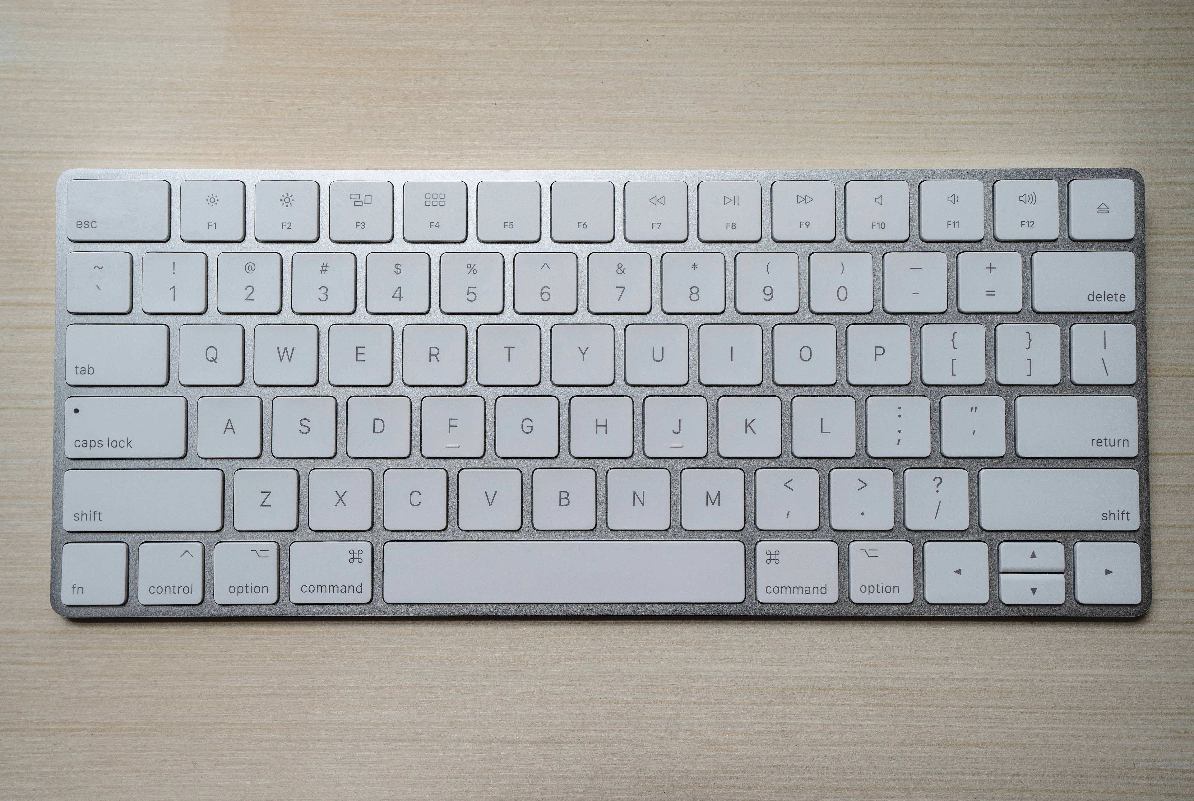 A slim white wireless keyboard on a white surface