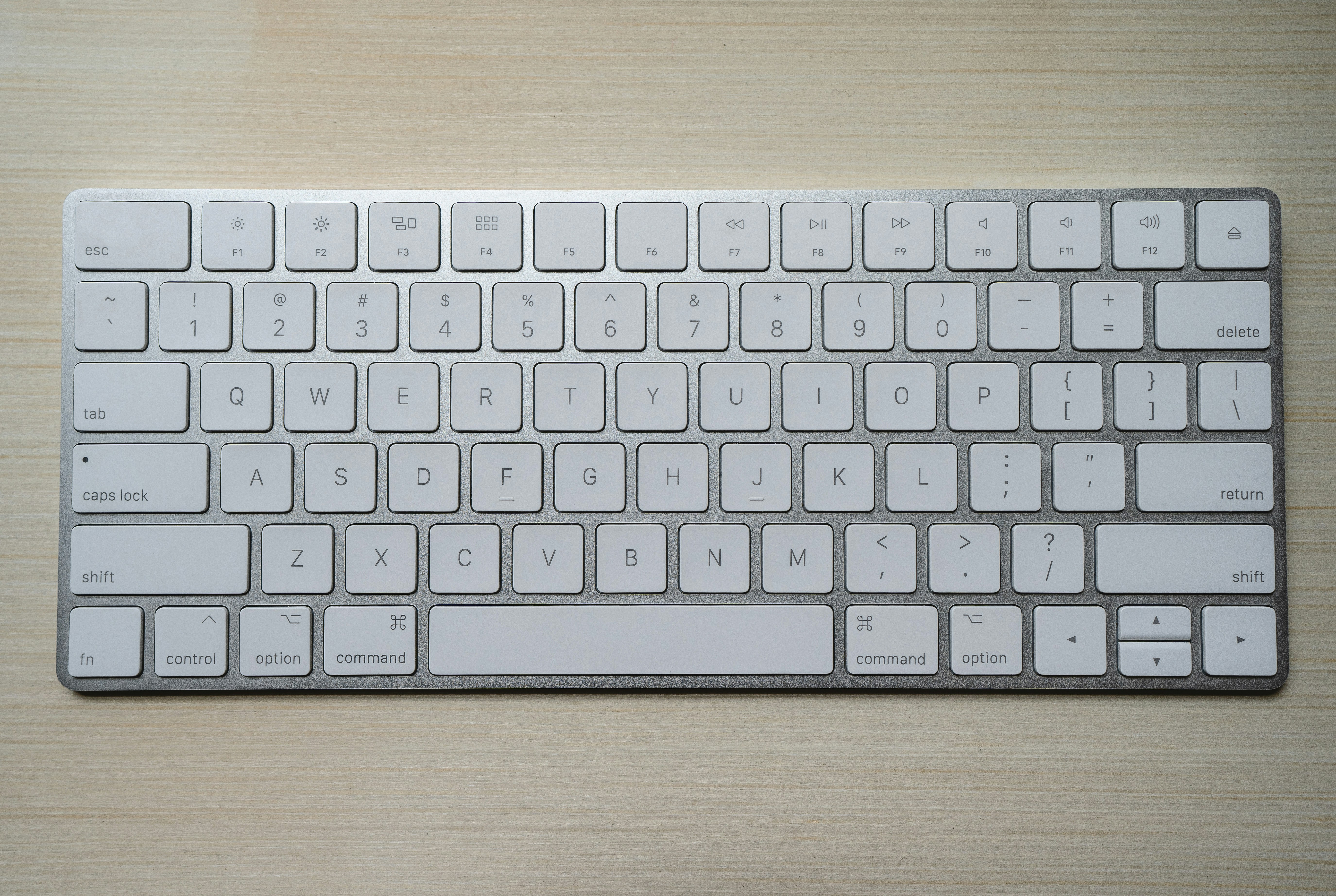 Minimal compact mechanical keyboard on a wood desk, clean neutral background