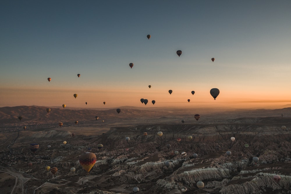 hot air balloons flying over the city during sunset