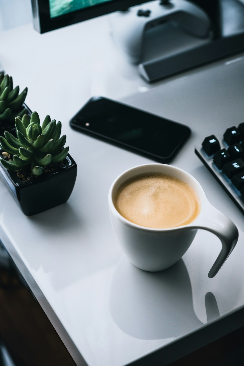 white ceramic mug beside black iphone 4