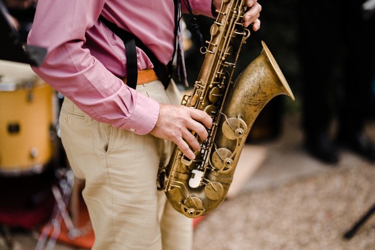 person in pink dress shirt playing saxophone