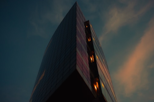 Close-up of a sleek glass skyscraper reflecting the soft gold hues of dawn.