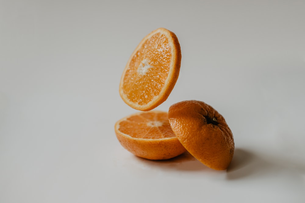 fruits orange tranchés sur une surface blanche
