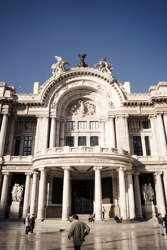 white concrete building under blue sky during daytime in Palacio de Bellas Artes Mexico