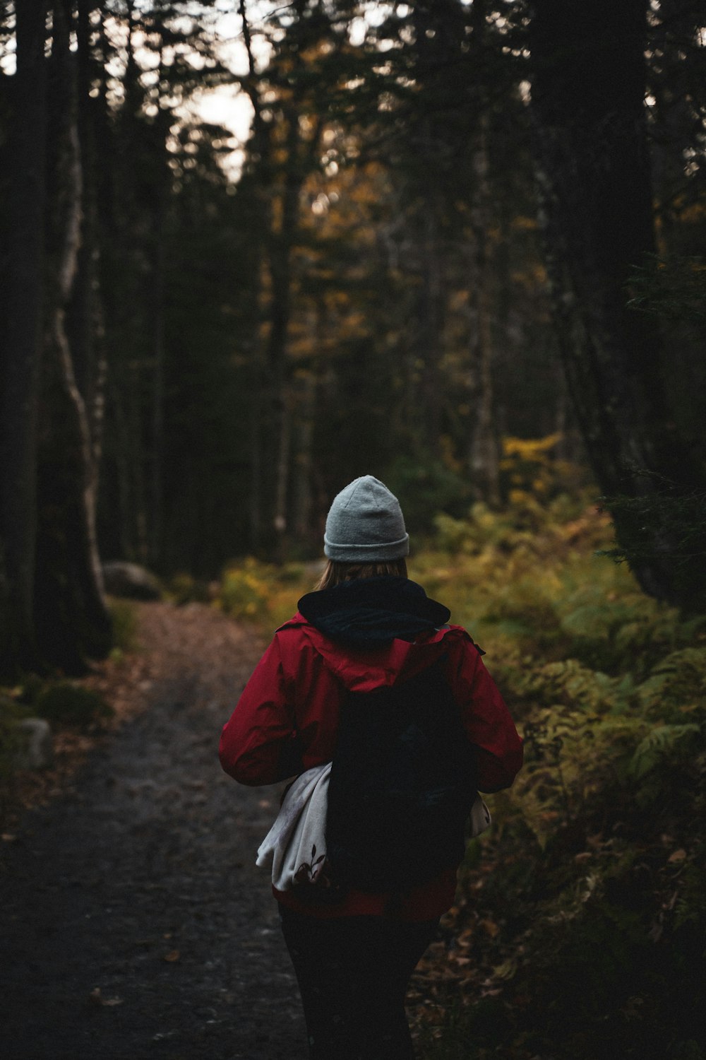 person in red jacket and white pants standing in forest during daytime