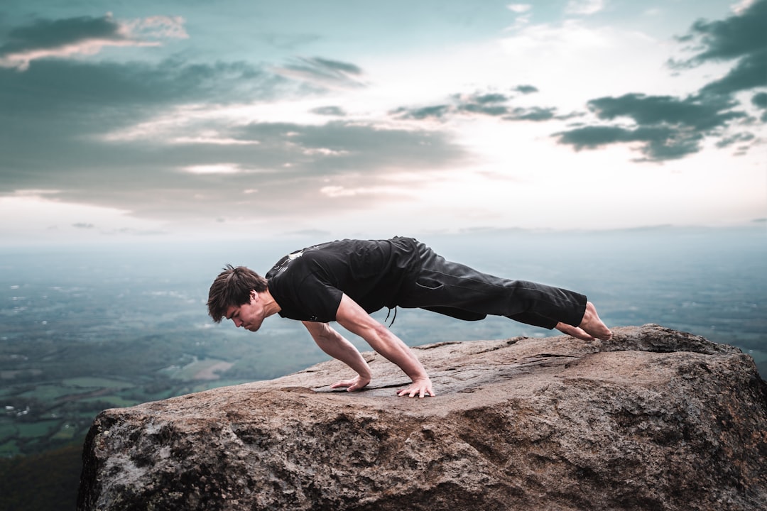 man in black t-shirt and black shorts sitting on brown rock formation during daytime