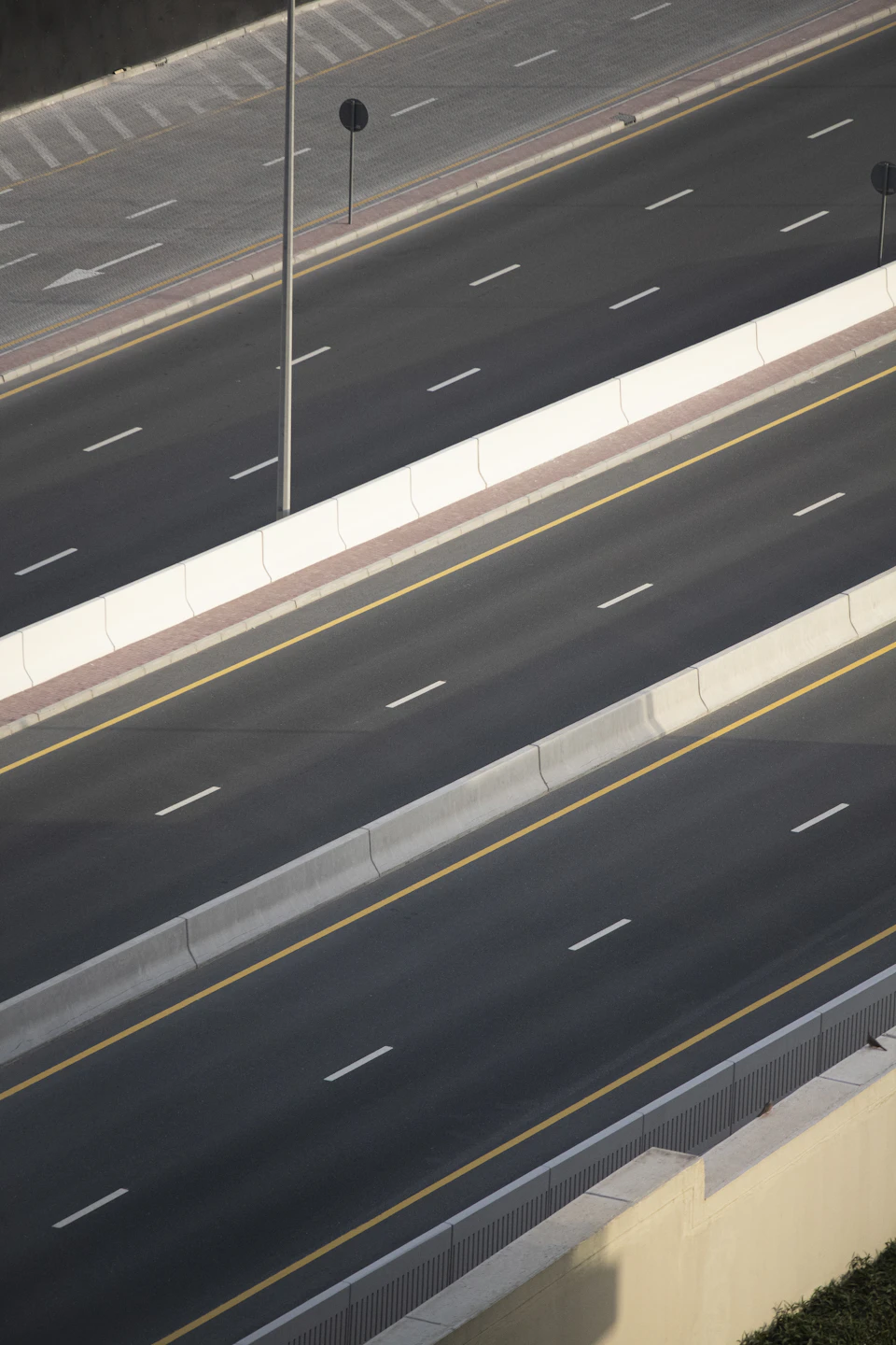 Two-lane highway with clear white lane markings and concrete barriers in rural landscape