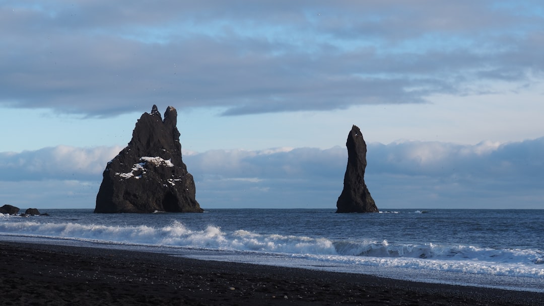 brown rock formation on sea under white clouds during daytime