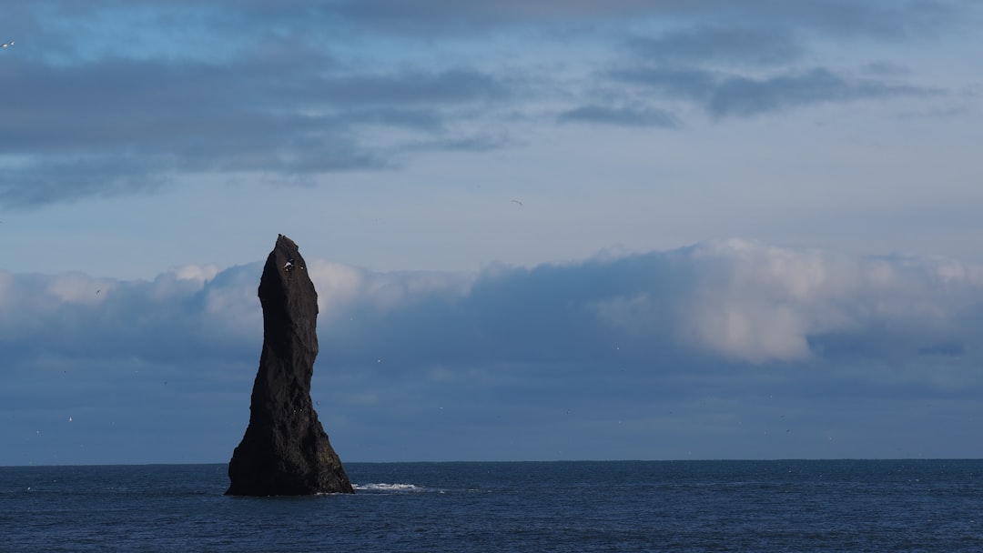 brown rock formation on sea under blue sky during daytime