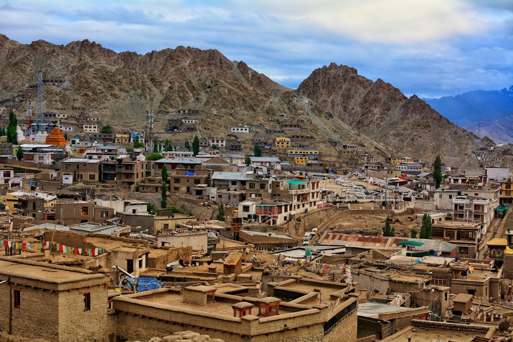 brown and white concrete buildings near brown mountain under white clouds during daytime